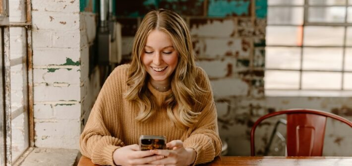 How to earn money using your phone: a woman looking at her phone at a table