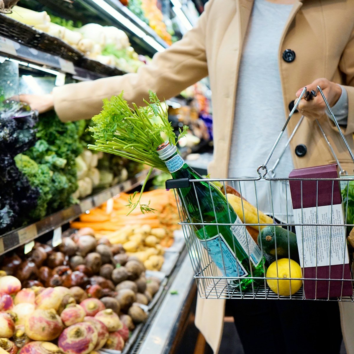 A woman pushing a shopping cart in a grocery store