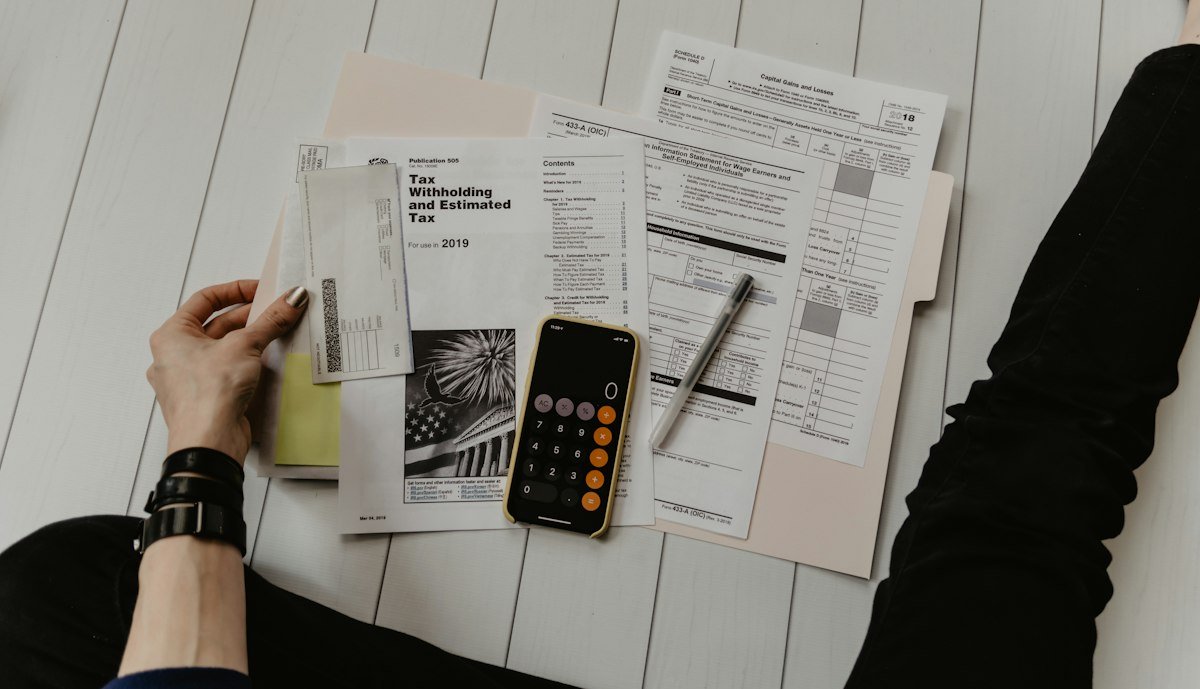 Hands holding a paper next to a pen and a calculator