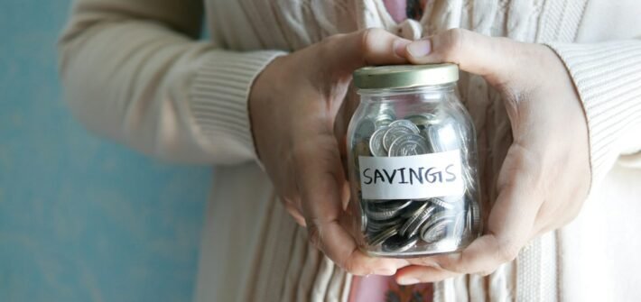 A woman holding a jar labeled savings