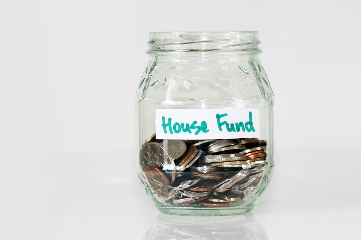 Coins in a glass jar labeled house fund